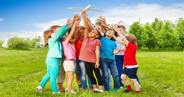 blog picture of children outside playing with a toy plane