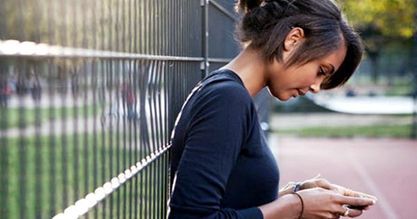 blog picture of teenage girl texting leaning up against a fence