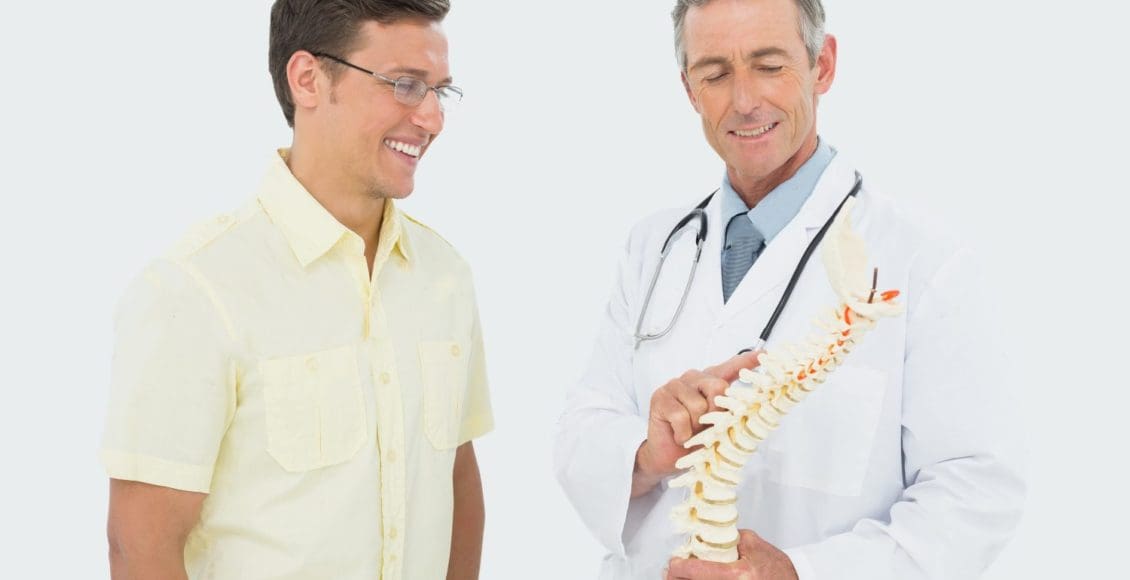 stock photo smiling male doctor showing patient something on skeleton model over white background
