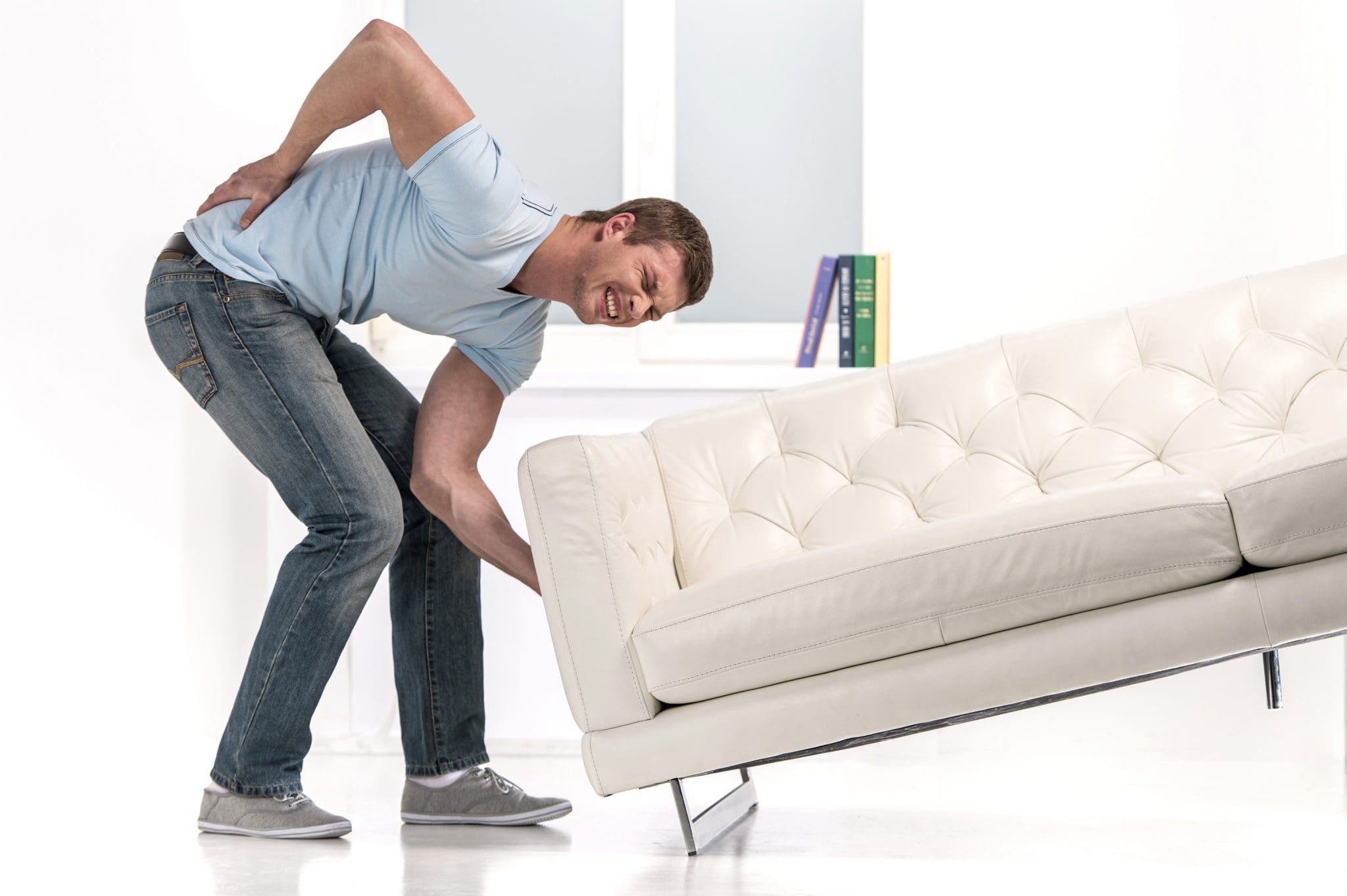 Болит поясница после тяжестей. Диван с подъемом для ног. Люди двигают диван. Двигать диван. Передвинуть диван.